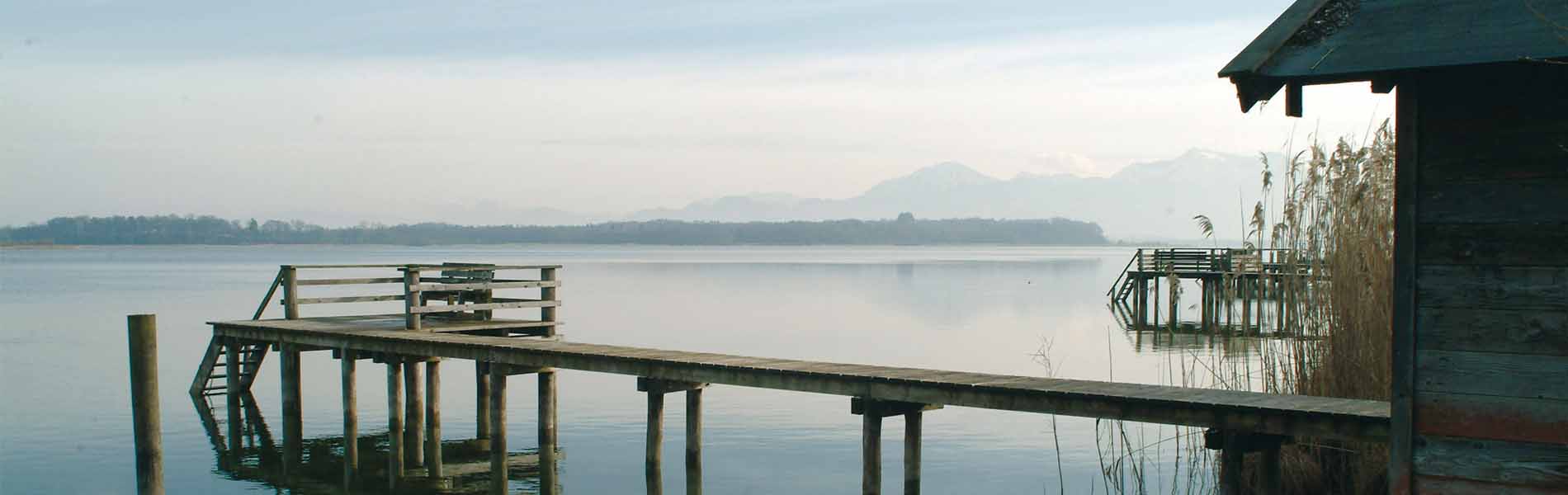 Eine braune Bootshütte mit einem Steg an einem großen See.