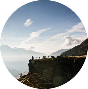 Eine Gruppe von Wanderern steht auf einem felsigen Bergrücken, umgeben von einer malerischen Gebirgslandschaft mit sanften Wolken .