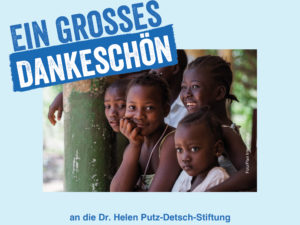 Eine Gruppe afrikanischer Kinder sitzt dicht beieinander und lächelt in die Kamera. Oben im Bild steht in großen blauen Buchstaben der Text „Ein großes Dankeschön“. Darunter steht: „an die Dr. Helen Putz-Detsch-Stiftung“.